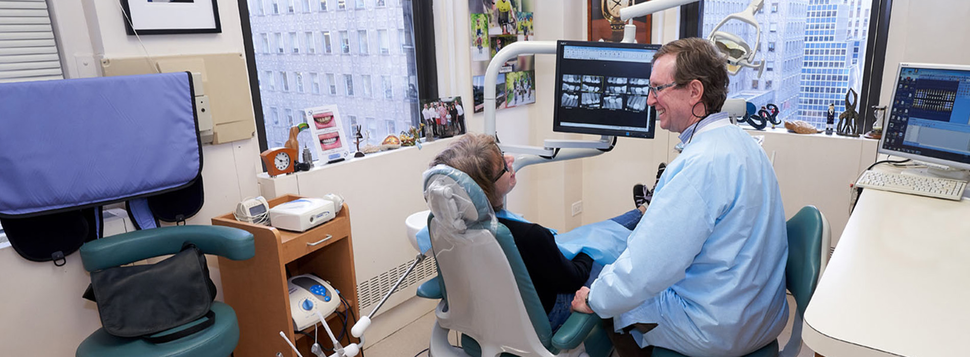 The image shows a dental office setting with a dentist seated at a chair, examining a patient s mouth.